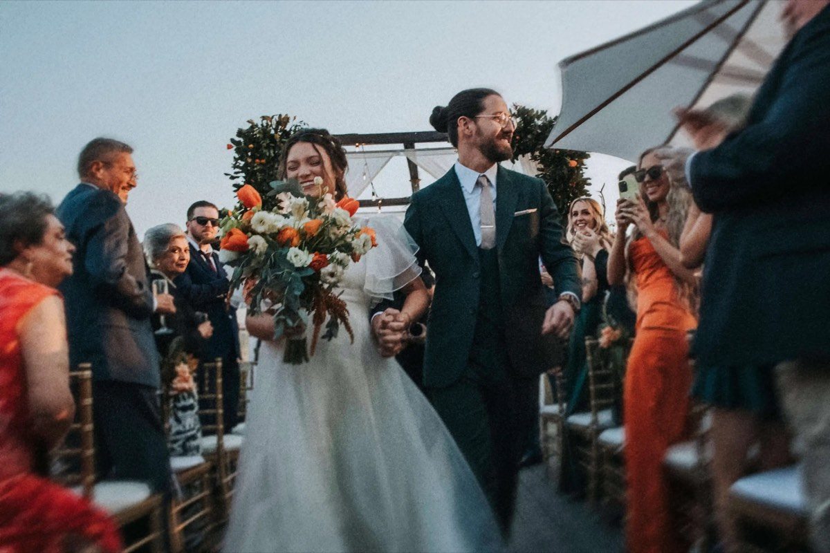 Novios saliendo de la ceremonia, invitados celebrando