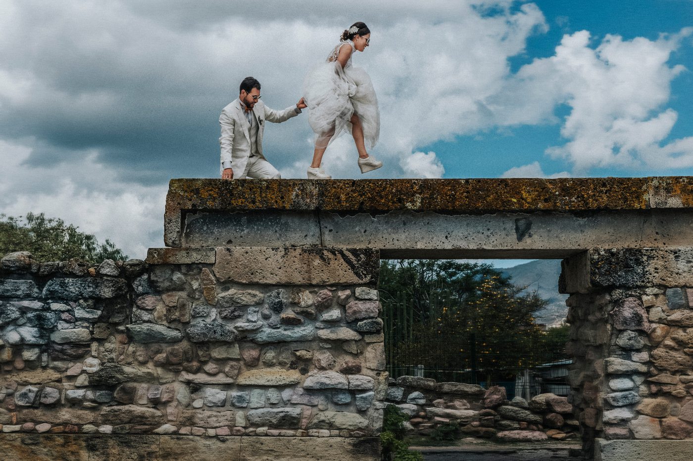 Novios caminando sobre un muro de piedra zapoteca en Mitla, Oaxaca