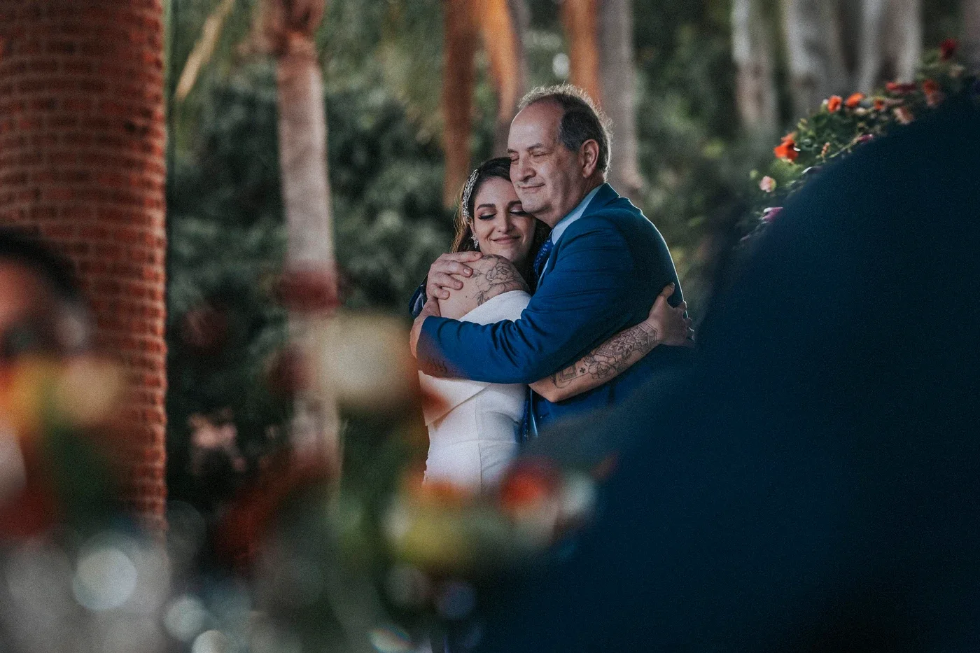 Lucía abrazando a su papá después de la ceremonia, entre los arcos de Quinta San Carlos