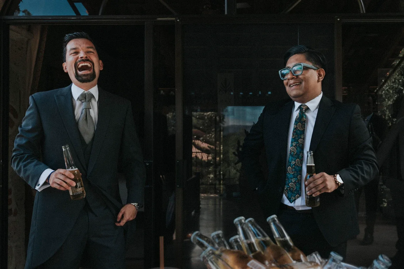 Padrinos del novio riendo y brindando con cerveza antes de la boda