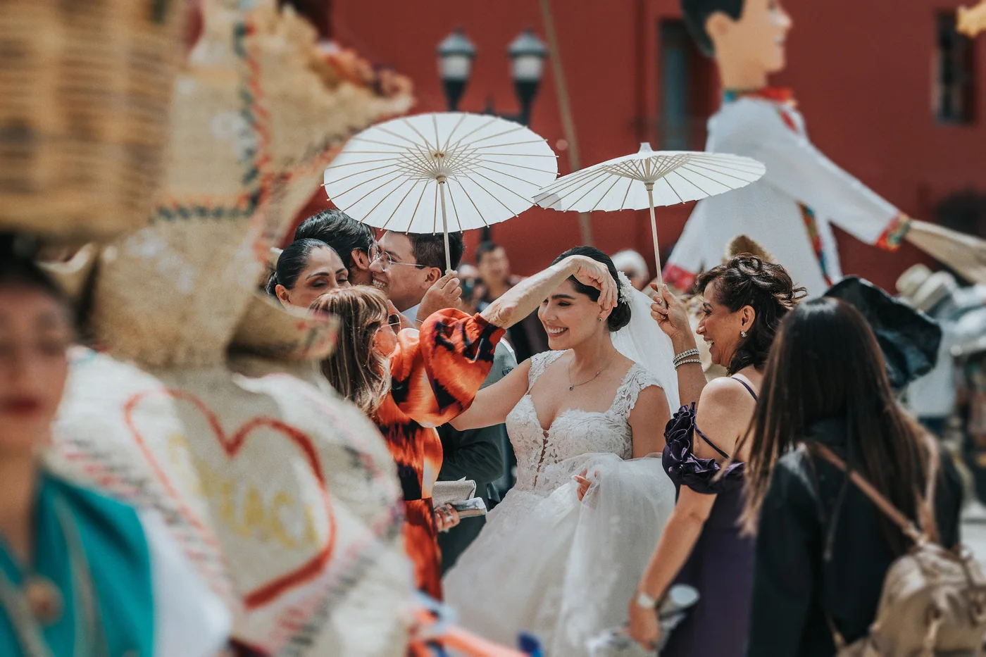 Marla sonríe bajo sombrillas blancas de papel en la calenda, junto al sombrero de palma de un tiliche