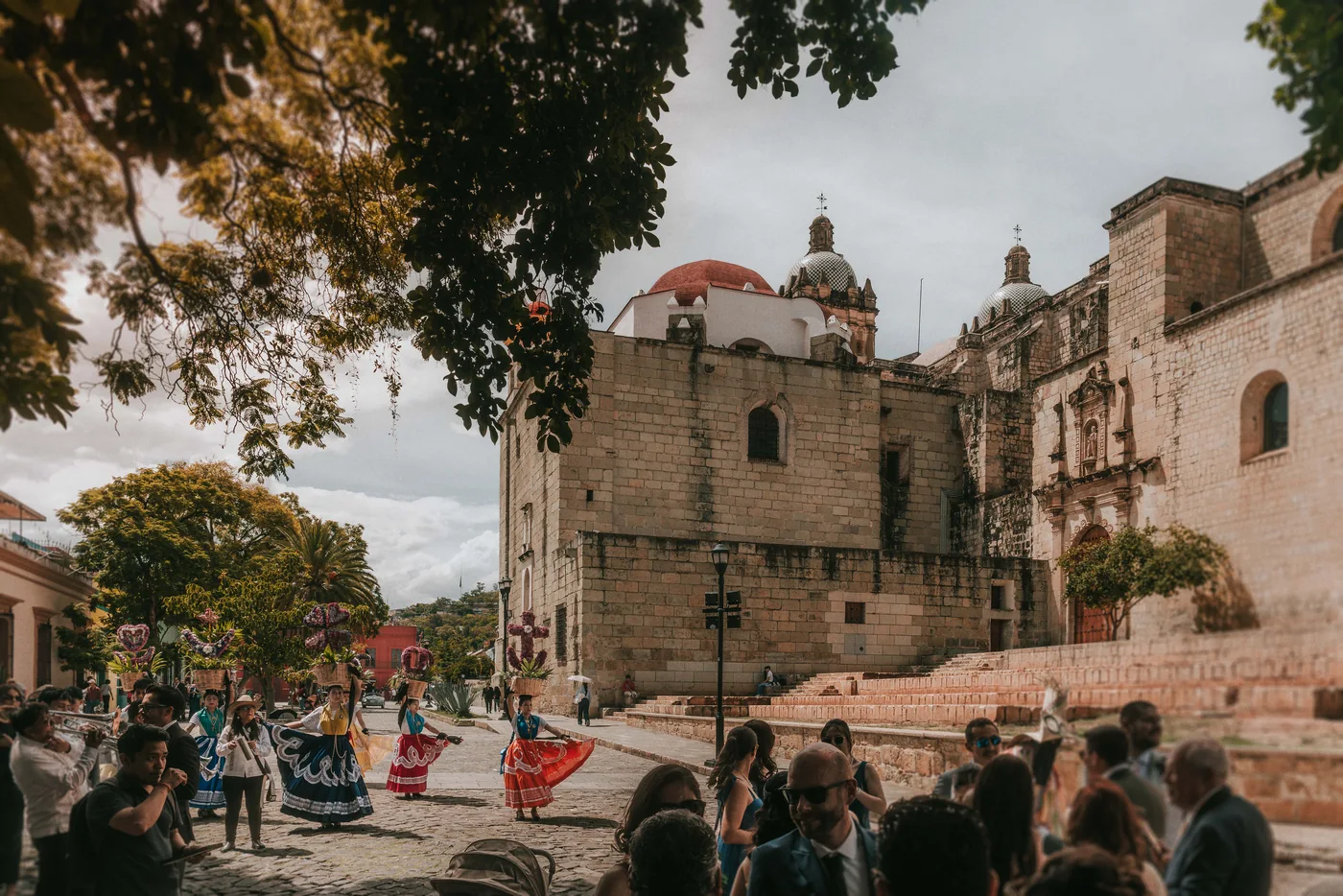 Chinas oaxaqueñas bailan en la calle junto al Templo de Santo Domingo mientras los invitados de la boda las miran