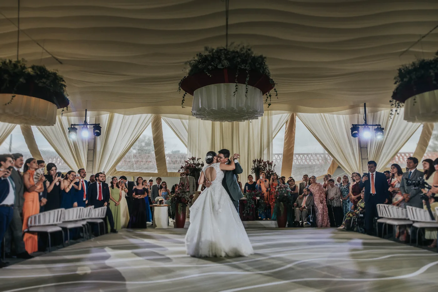 Primer baile de Marla y Edy bajo la carpa de Lisianthus, rodeados de invitados