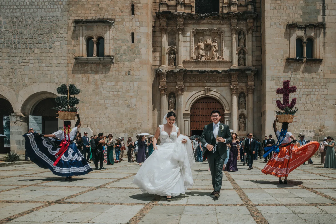 Marla y Edy cruzan el atrio de Santo Domingo entre chinas oaxaqueñas que bailan con canastas de flores en la cabeza
