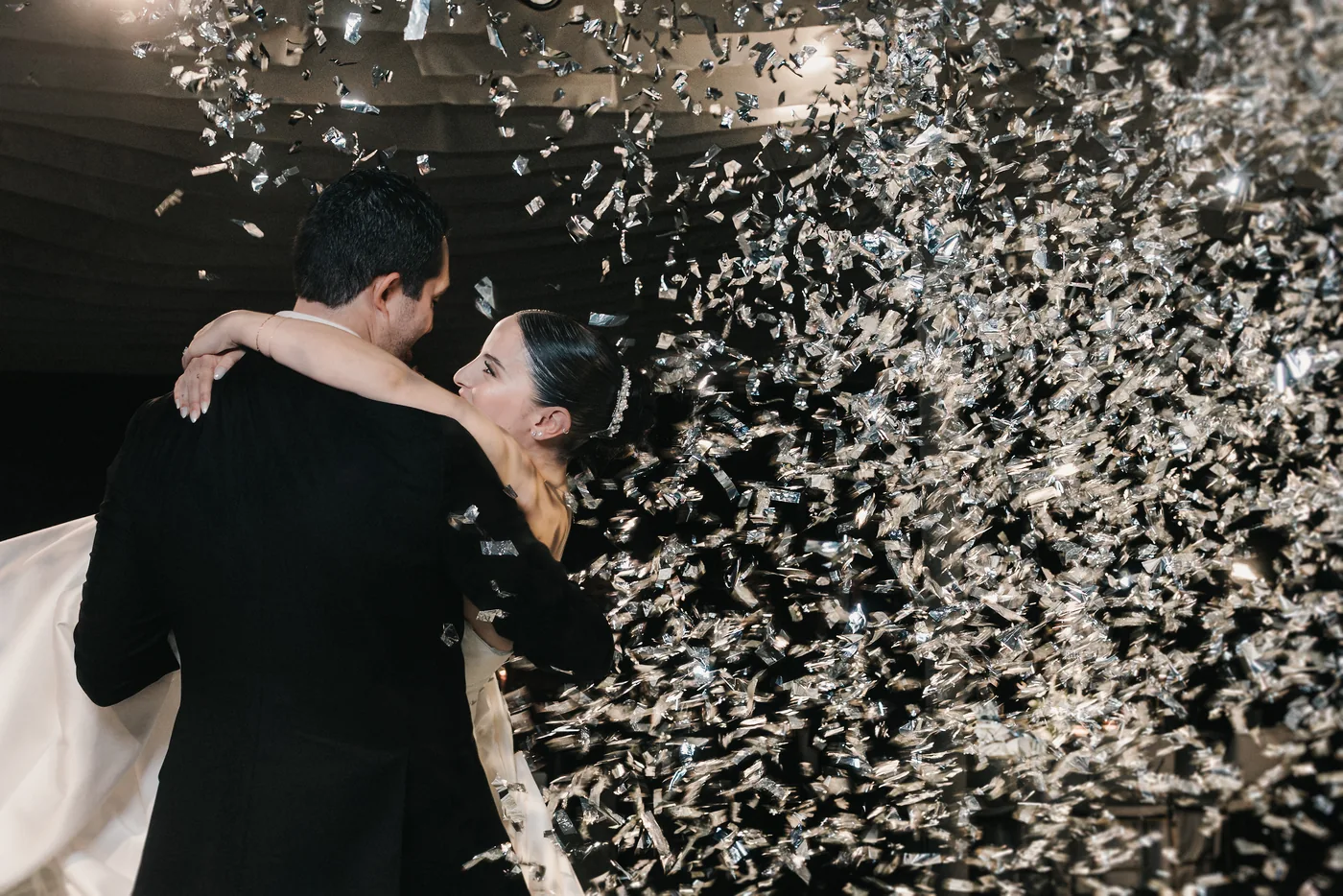 Sofi y Diego abrazados bajo una lluvia de confeti plateado