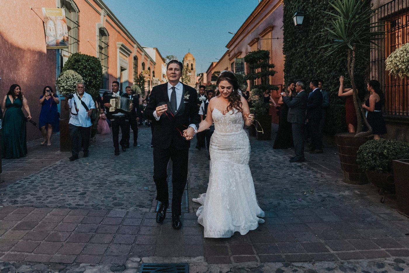 Novia y su padre caminando por una calle empedrada de Tequila durante la callejoneada