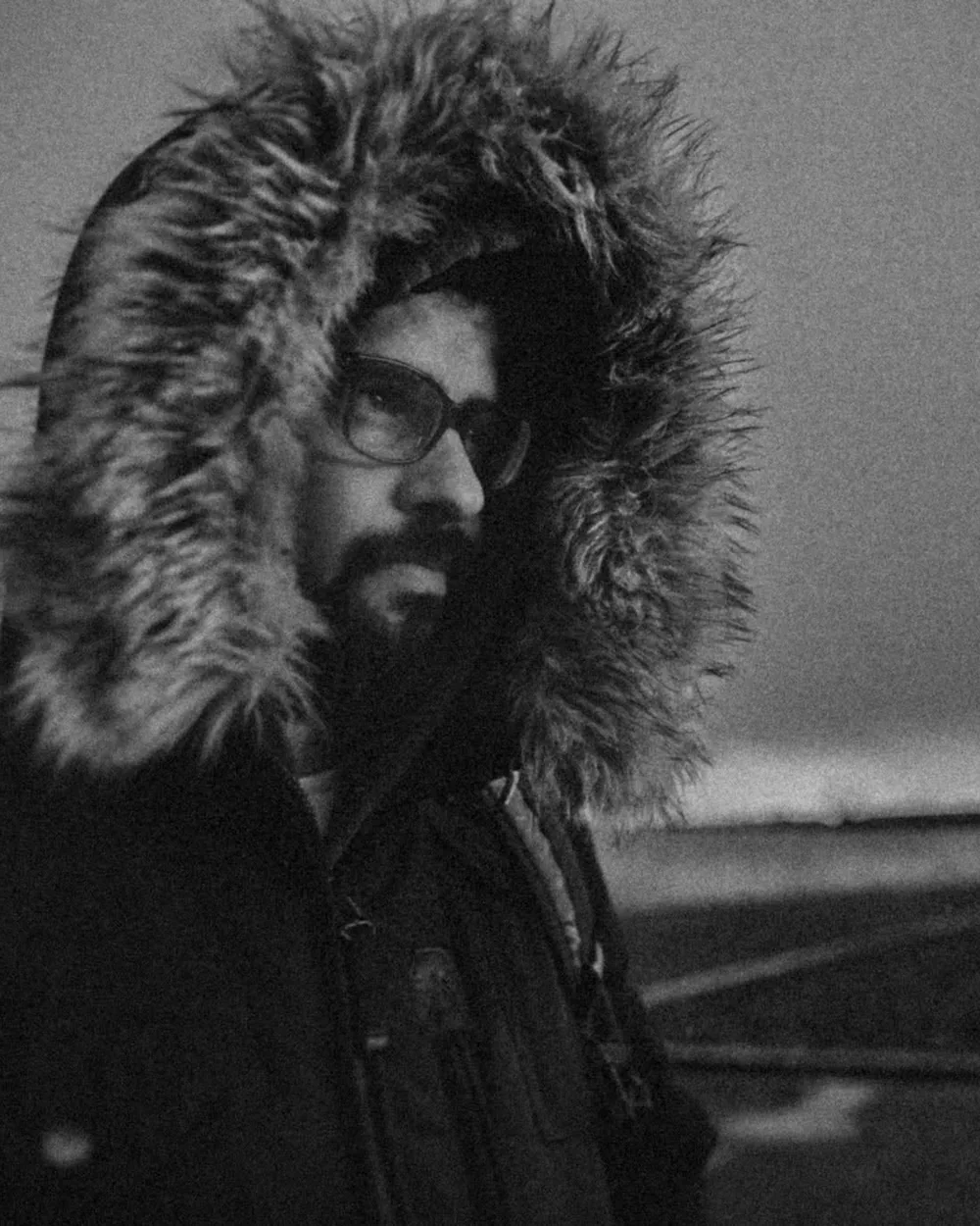 Christian Macías, fotógrafo de bodas documental, retrato en blanco y negro al aire libre con parka de capucha