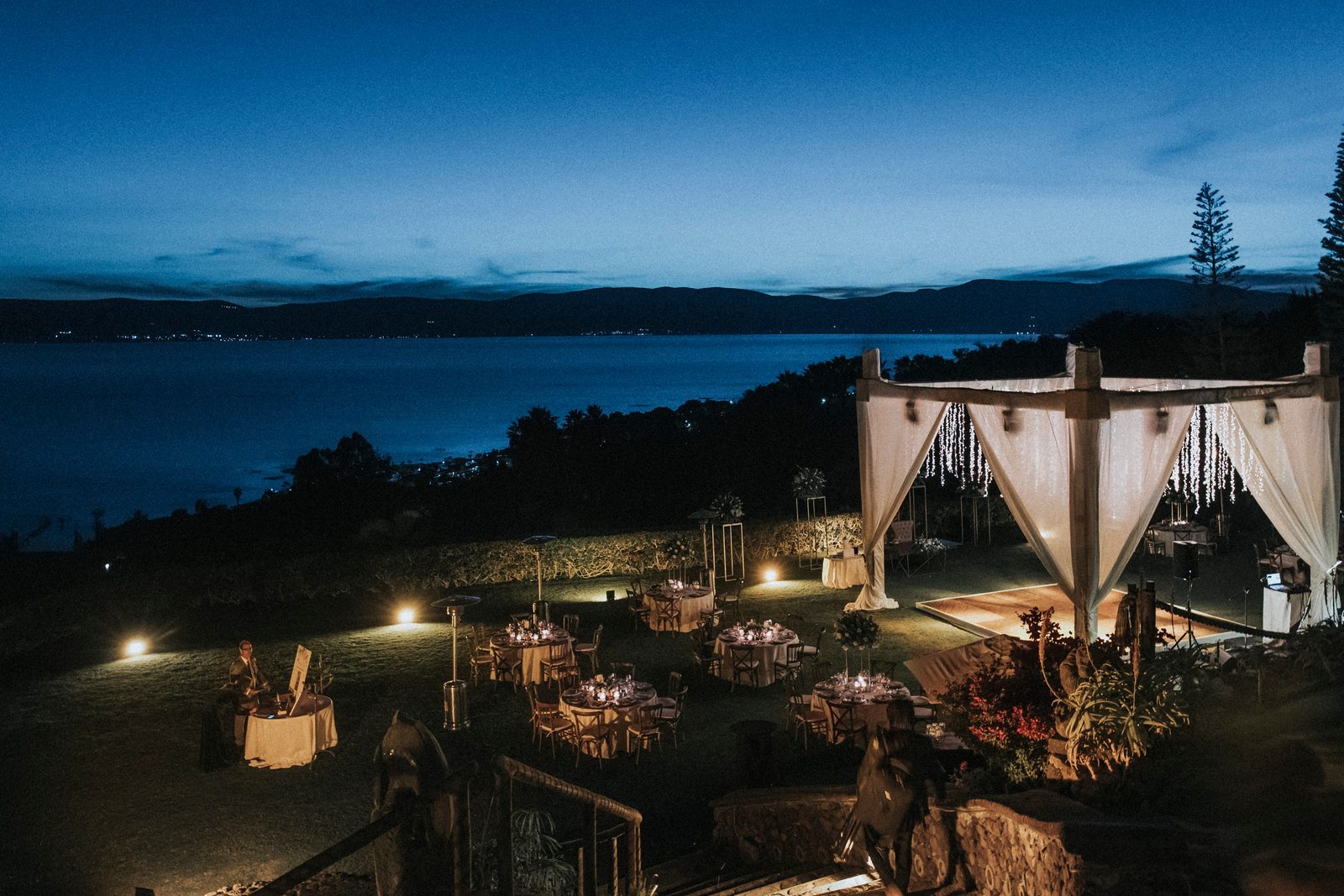 Toldo montado sobre la cena de boda en Monte Coxala durante la hora azul, con el lago de Chapala detrás
