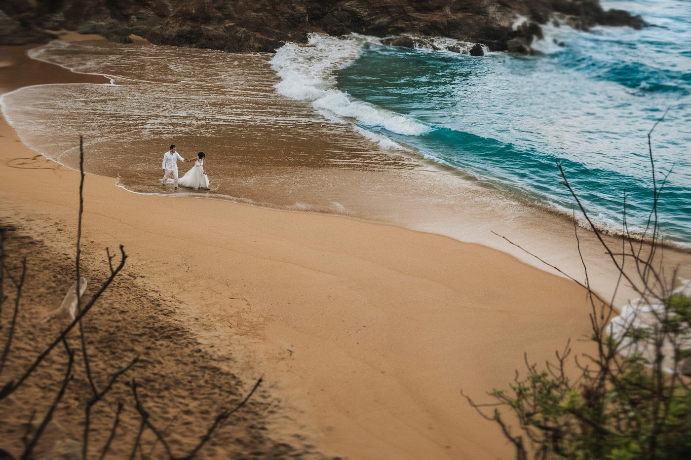 Novios diminutos caminando por una playa vacía en Mazunte, Oaxaca, al amanecer
