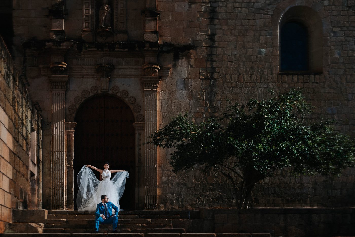 Los novios en la escalinata de una portada lateral de Santo Domingo, con la cantera iluminada a primera hora